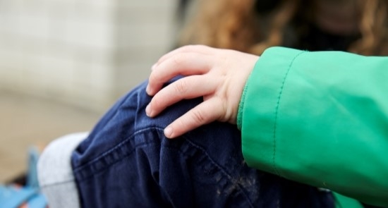 A child's hand on their knee)