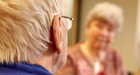 The back of a man's head with a woman who's looking at him, she is out of focus)