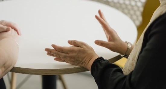 A woman's hands resting on a table)